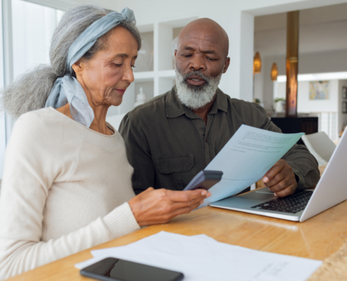 Couple discussing papers and using laptop inside a room