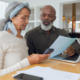 Couple discussing papers and using laptop inside a room