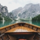 a picture of a wooden boat traveling through a river surrounded by snow covered mountains